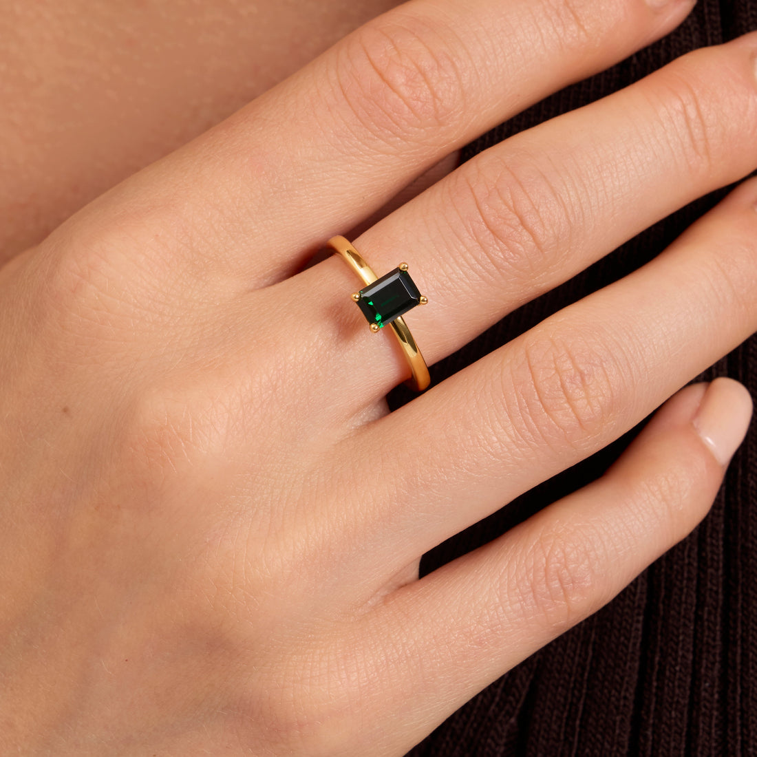 Emerald birthstone ring shown on model finger 